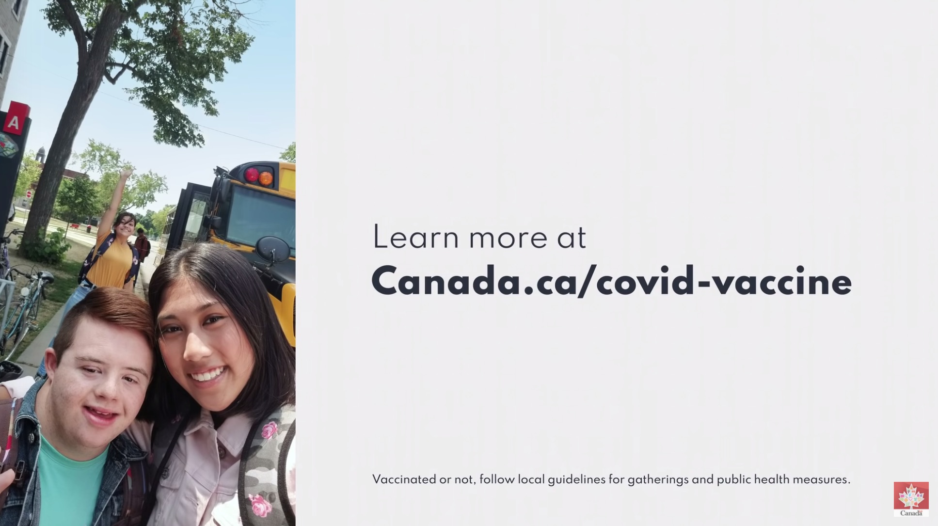 A screenshot from a Youtube and television advertisement published by the Public Health Agency of Canada. It shows a teacher and student taking a selfie next to a school bus on the left, and the text “Learn more at Canada.ca/covid-vaccine” on the right. In small text at the bottom it says, “Vaccinated or not, follow local guidelines for gatherings and public health measures.”.