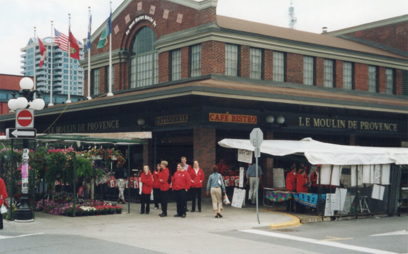 Members of the Vanier Collegiate chamber choir, wearing matching red bunnyhugs and standing in front of the Moulin de Provence in Ottawa’s Byward Market in 2004.