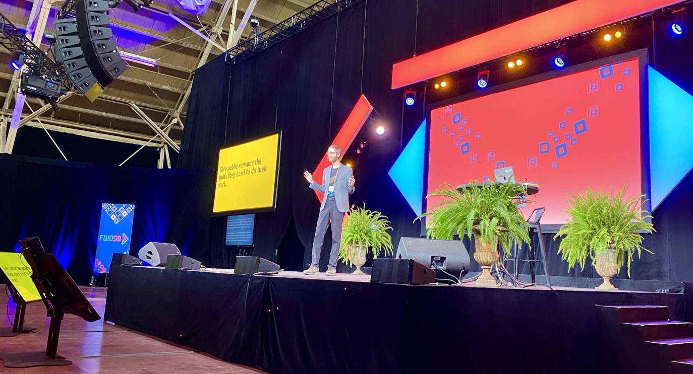 Me presenting on stage at FWD50 with slides titled ”Give public servants the tools they need to do their job”.